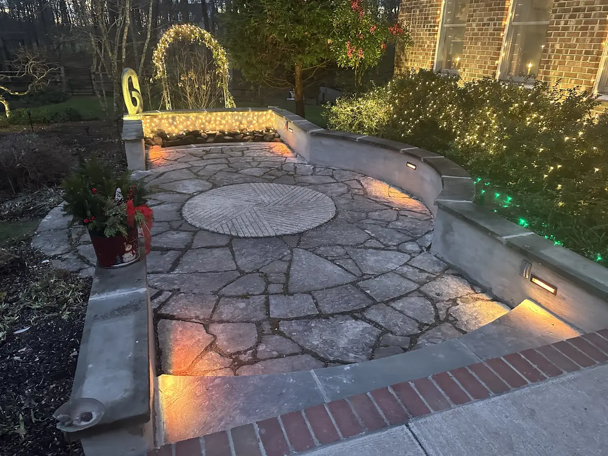Flagstone courtyard patio with lit seating walls at dusk by MG Minor Construction in Marshall VA